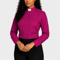 Woman wearing a magenta shirt with a white collar against a plain background