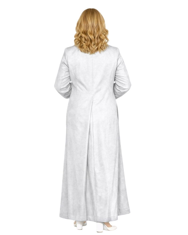 A woman viewed from behind wearing a long white or off-white long cassock with long sleeves, standing against a plain white background.