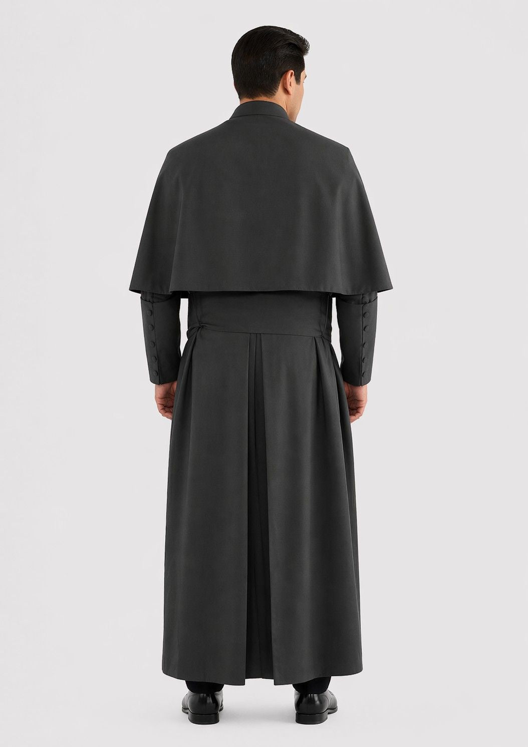 Man wearing a long dark gray cassock on a light white background