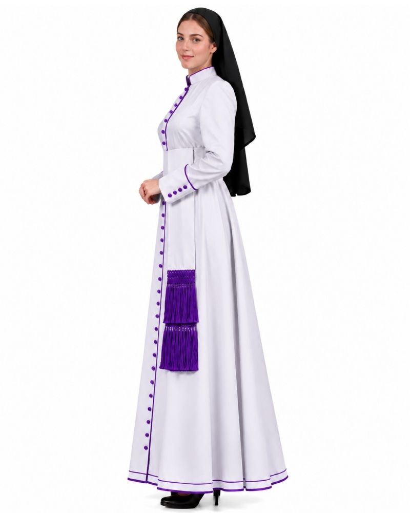 A woman modeling a white nun's habit dress with purple trim, buttons, and a purple sash, paired with a black veil, against a plain white background.