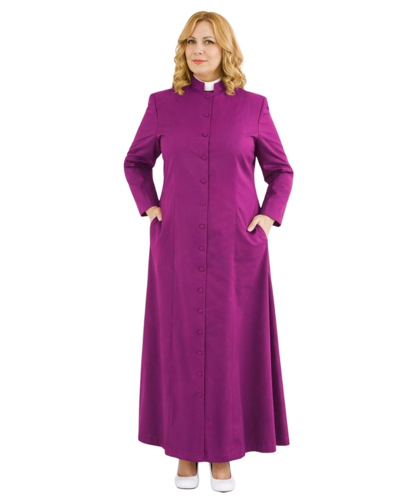 A woman modeling a long magenta-purple robe with a high collar, front buttons, and side pockets, paired with a white clerical collar, on a plain white background.