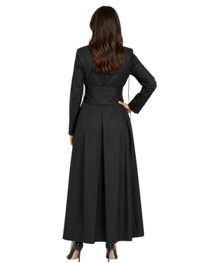 A woman shown from the back wearing a long black cassock or robe with long sleeves, a defined waist, and a full skirt, paired with black heels against a plain white background.