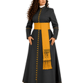 A woman modeling a long black cassock with a wide mustard yellow sash, matching yellow buttons down the front, and yellow piping details, set against a plain white background.