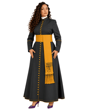 A woman modeling a long black cassock with a wide mustard yellow sash, matching yellow buttons down the front, and yellow piping details, set against a plain white background.