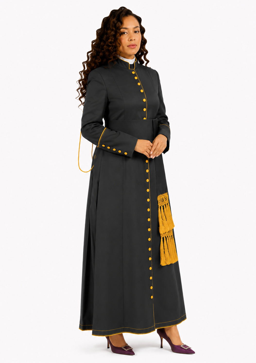 Woman wearing a black robe with yellow buttons and a fringed detail on a white background