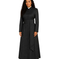 A woman modeling a long black cassock with a high stand collar, front button closure, and a matching waist tie, shown against a plain white background.