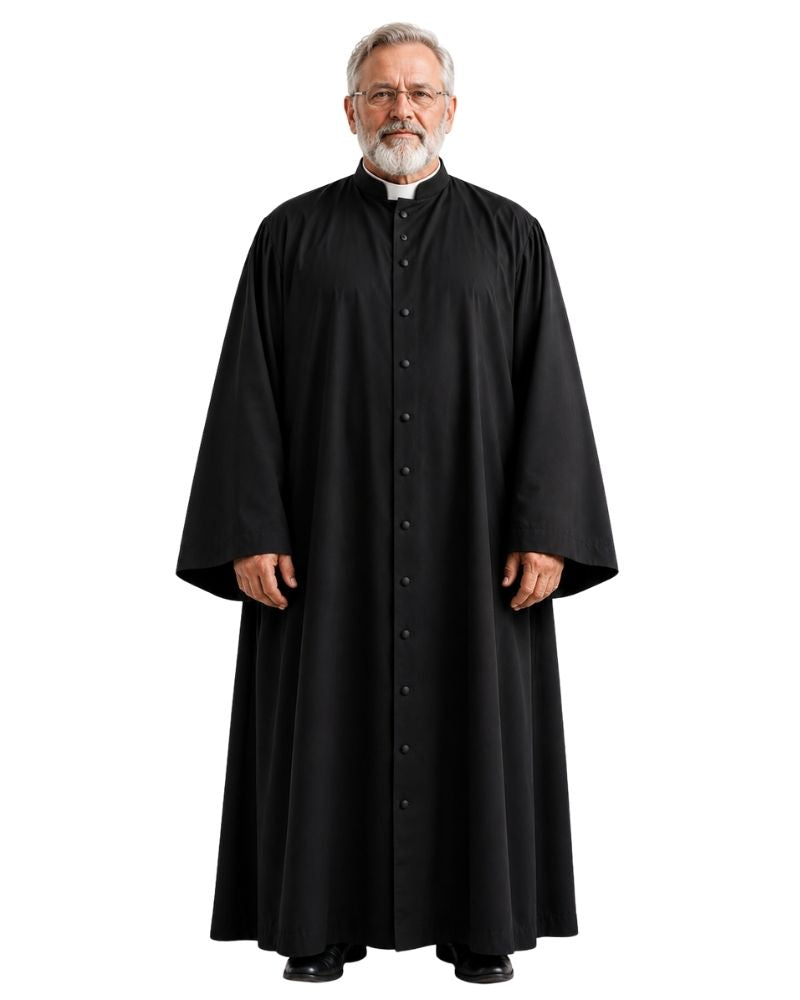 A man wearing a long black clerical robe with a high collar and front buttons, standing against a plain white background.