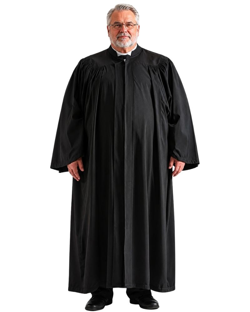 A man wearing a black robe stands against a plain white background. The robe has a high collar, long sleeves, and a front opening with a black tie.