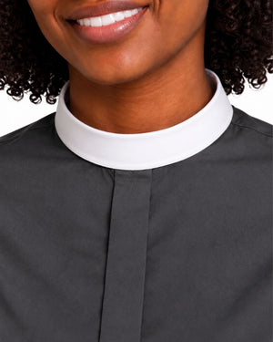 Close-up of a woman wearing a dark charcoal gray clerical shirt with a contrasting white collar.
