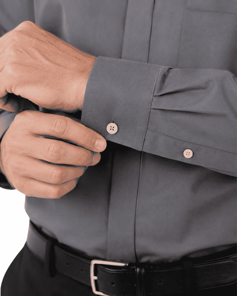 Close-up of a man's hands adjusting the cuff of a gray clerical shirt, with a black belt visible at the bottom.