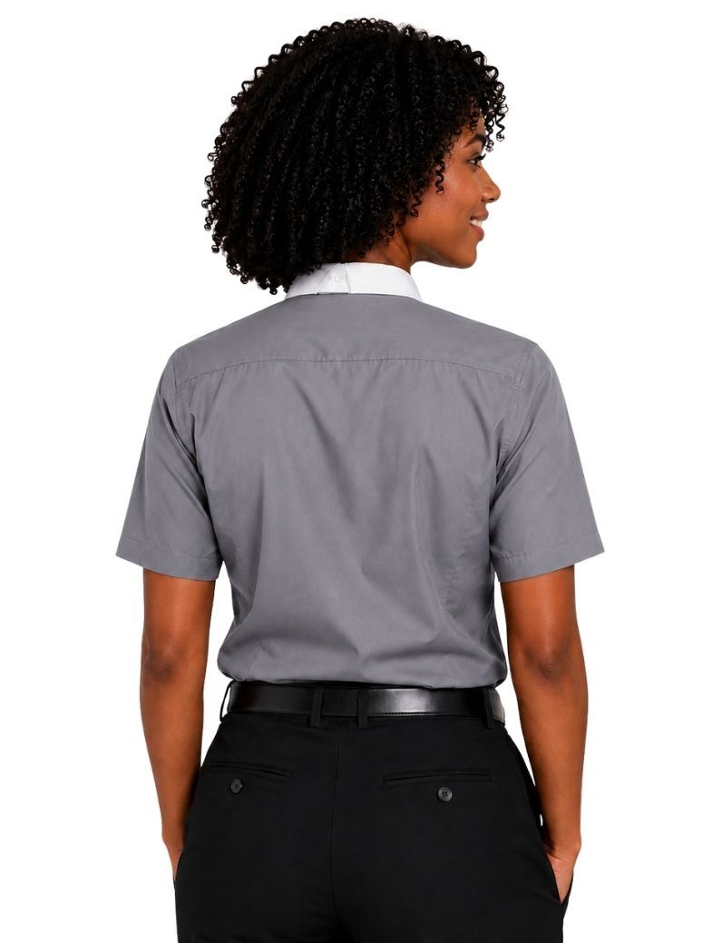 A woman shown from the back wearing a short-sleeve gray clerical shirt tucked into black pants, against a plain white background.