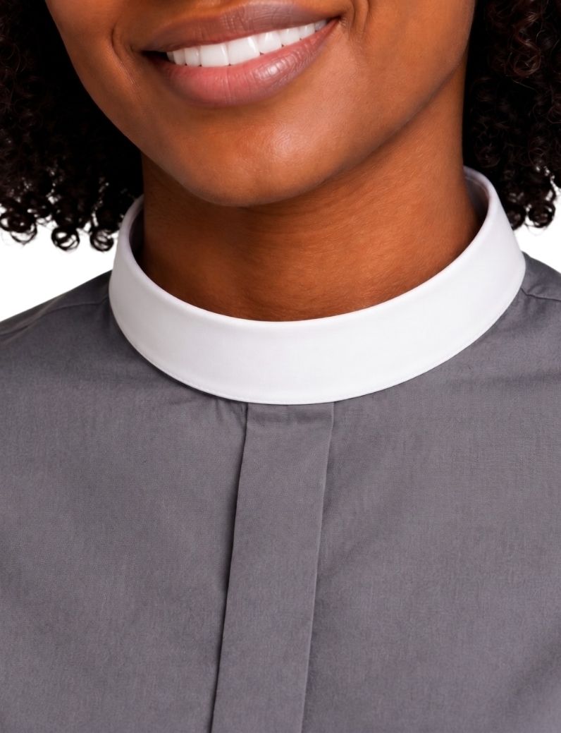 Close-up of a woman wearing a gray clerical shirt with a contrasting white collar, cropped from the mouth down against a plain light background.