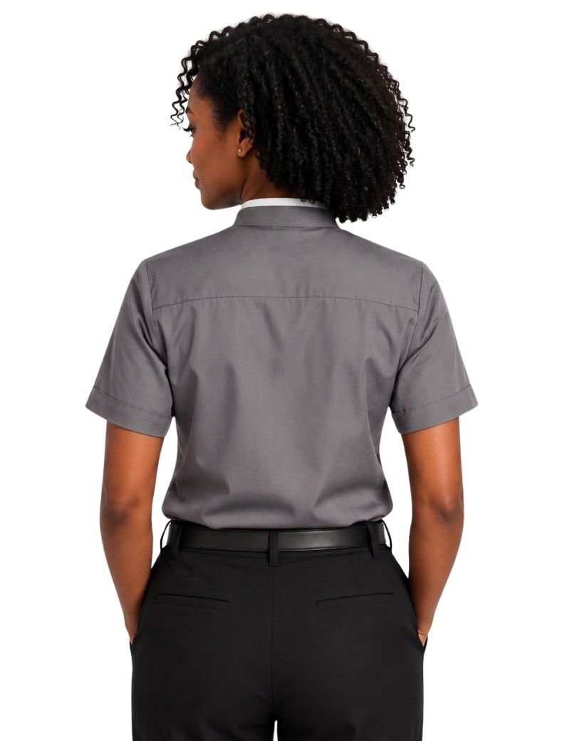 A woman shown from the back wearing a short-sleeve gray clerical shirt tucked into black pants, against a plain white background.