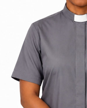 A close-up of a woman wearing a short-sleeve gray clerical shirt with a white collar, shown against a plain white background.