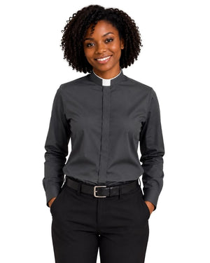 A smiling woman with curly black hair wearing a dark gray long-sleeve clerical shirt with a white collar, paired with black trousers and a black belt, against a plain white background.