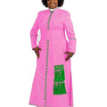 A woman modeling a bright pink long-sleeve cassock with green trim, decorative green buttons, and a green fringe panel on the front, set against a plain white background.
