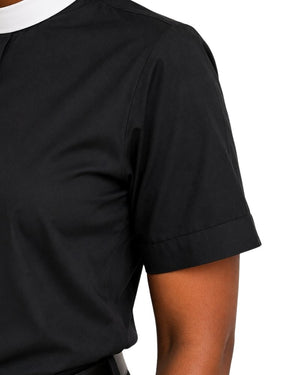 Close-up of a women wearing a black short-sleeve collared clerical shirt with a white collar trim, shown against a plain white background.