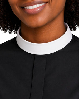 Close-up of a women wearing a black top with a contrasting white high collar, cropped from the mouth down against a plain light background.