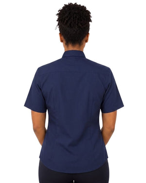 A woman viewed from the back wearing a navy blue short-sleeve clerical shirt and dark pants, set against a plain white background.