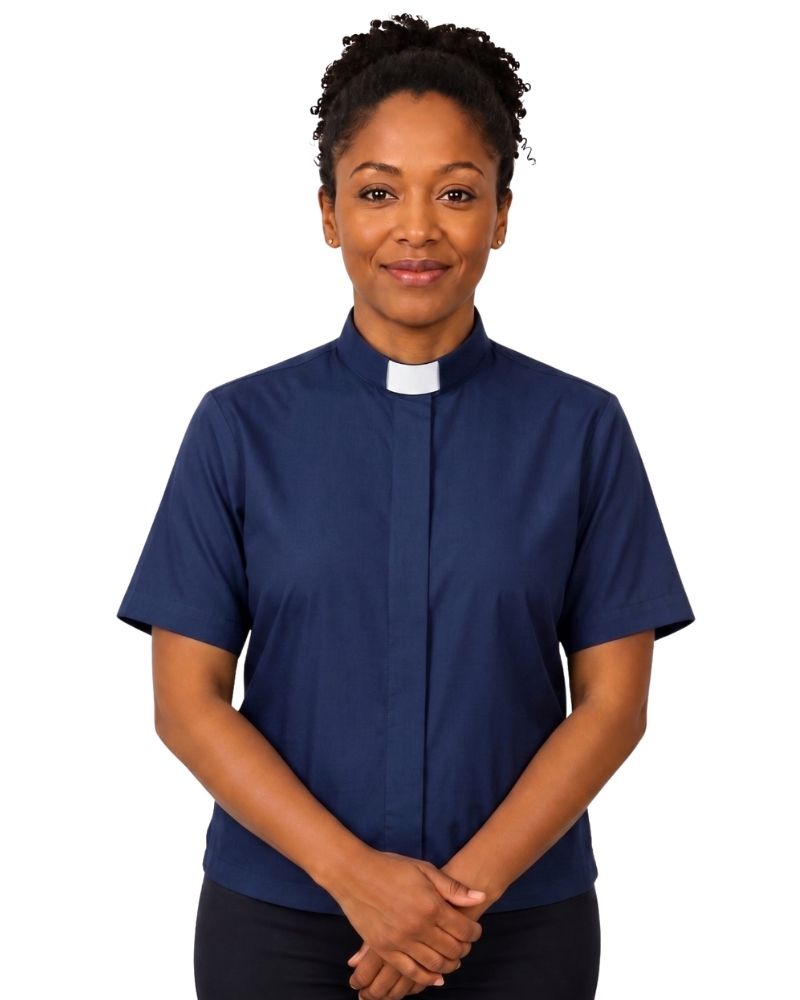 A woman wearing a navy blue short-sleeve clerical shirt with a white collar, standing against a plain white background.