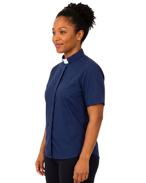 A woman wearing a navy blue short-sleeve button-up shirt with a white clerical collar, shown in profile against a plain white background.