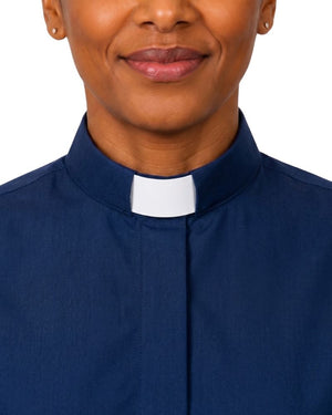A close-up of a women wearing a navy blue clerical shirt with a white clerical collar, shown against a plain white background.