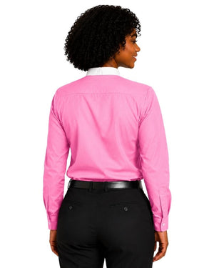 A woman shown from the back wearing a bright pink long-sleeve clerical shirt tucked into black pants with a black belt, against a plain white background.