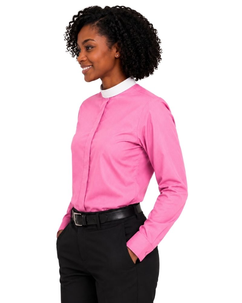 A woman wearing a bright pink long-sleeve clerical shirt with a contrasting white collar, paired with black trousers and a black belt, shown against a plain white background.