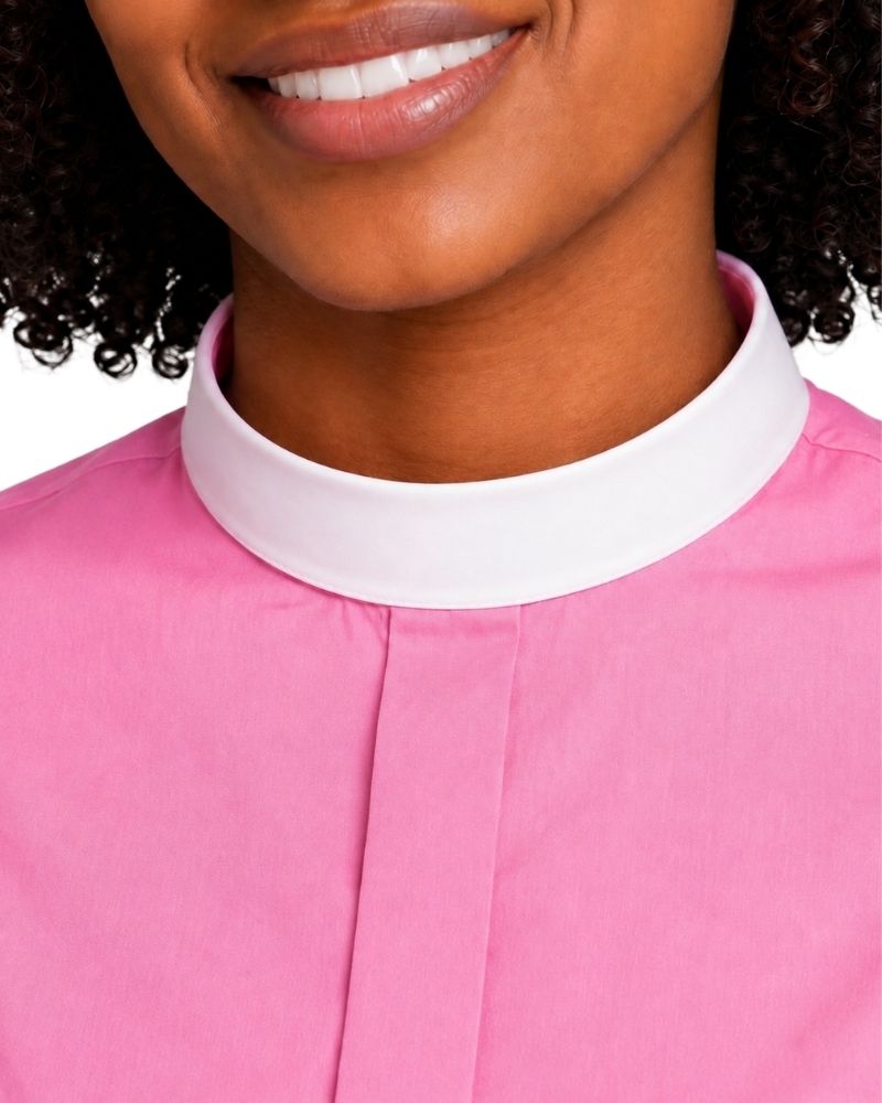 Close-up of a woman wearing a pink clerical shirt with a contrasting white high collar, cropped from the mouth to the chest against a plain white background.