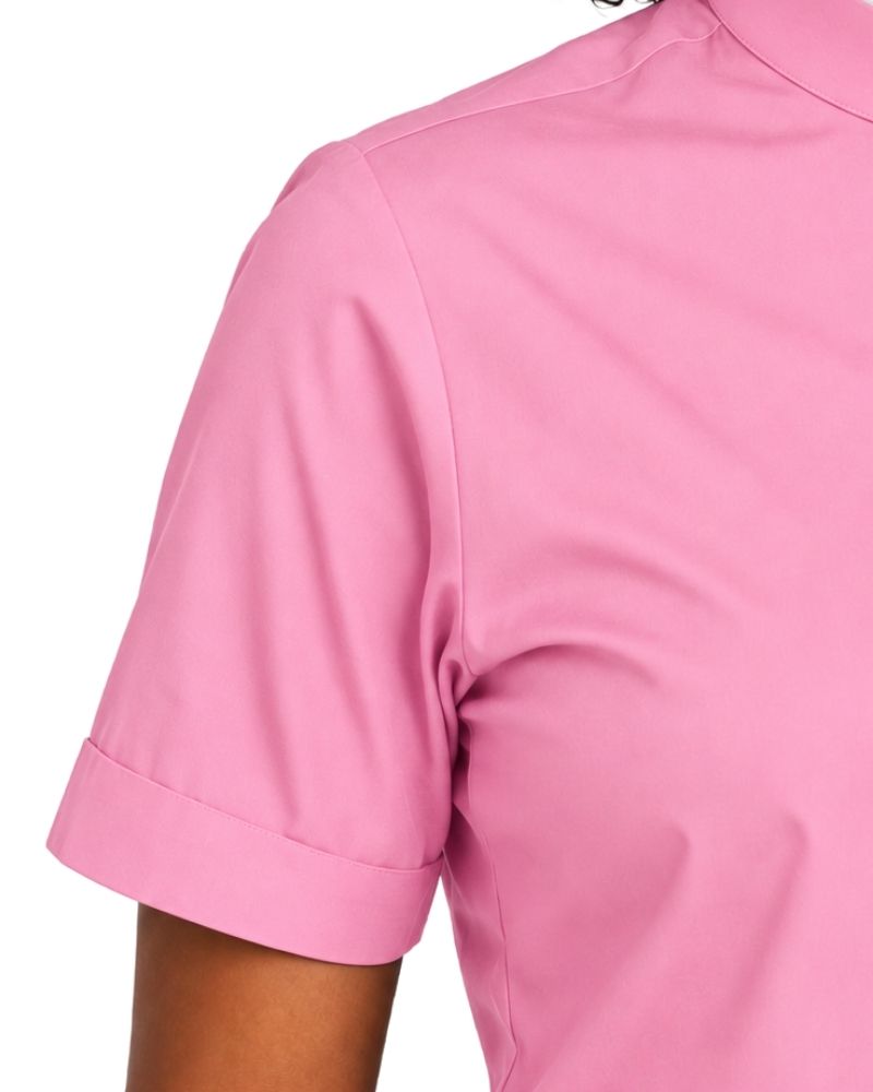 Close-up of a pink short-sleeve clerical shirt on a model, showing the shoulder, sleeve cuff, and upper torso against a plain white background.