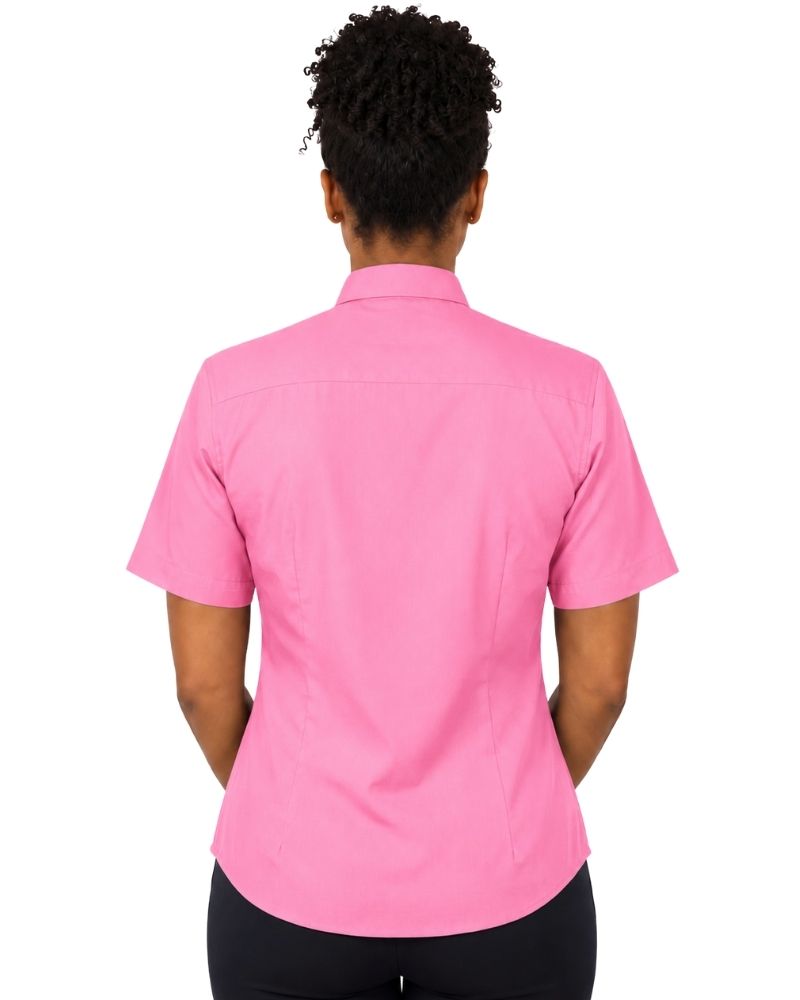 A woman viewed from the back wearing a short-sleeve pink clerical shirt and black pants, set against a plain white background.