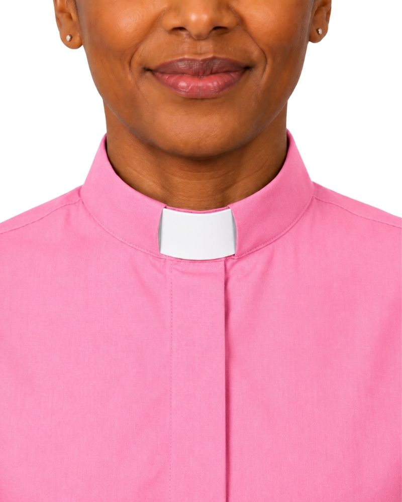 A close-up of a women wearing a bright pink clerical shirt with a white collar tab, shown against a plain white background.