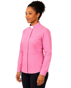 A woman wearing a pink long-sleeve clerical shirt with a white collar, paired with black trousers, shown from the waist up against a plain white background.