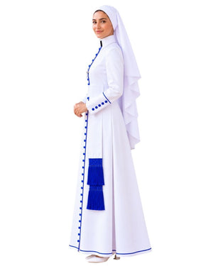 A woman modeling a White Anglican Cassock with a matching head covering, featuring royal blue trim, decorative buttons, and a tassel detail, set against a plain white background.