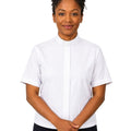 A woman wearing a white short-sleeve clerical shirt with a collar, paired with black trousers, standing against a solid white background.