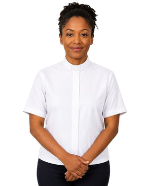 A woman wearing a white short-sleeve clerical shirt with a collar, paired with black trousers, standing against a solid white background.