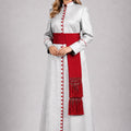 Woman wearing a long white dress with red accents on a plain background