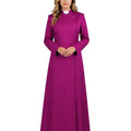 A woman modeling a long magenta-purple cassock with a white collar, standing against a plain white background.