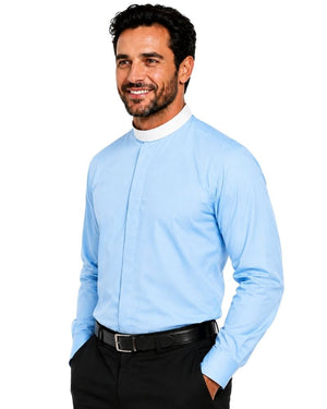 A smiling man wearing a light blue long-sleeve clerical shirt with a white mock neck collar, paired with black trousers and a black belt, against a plain white background.