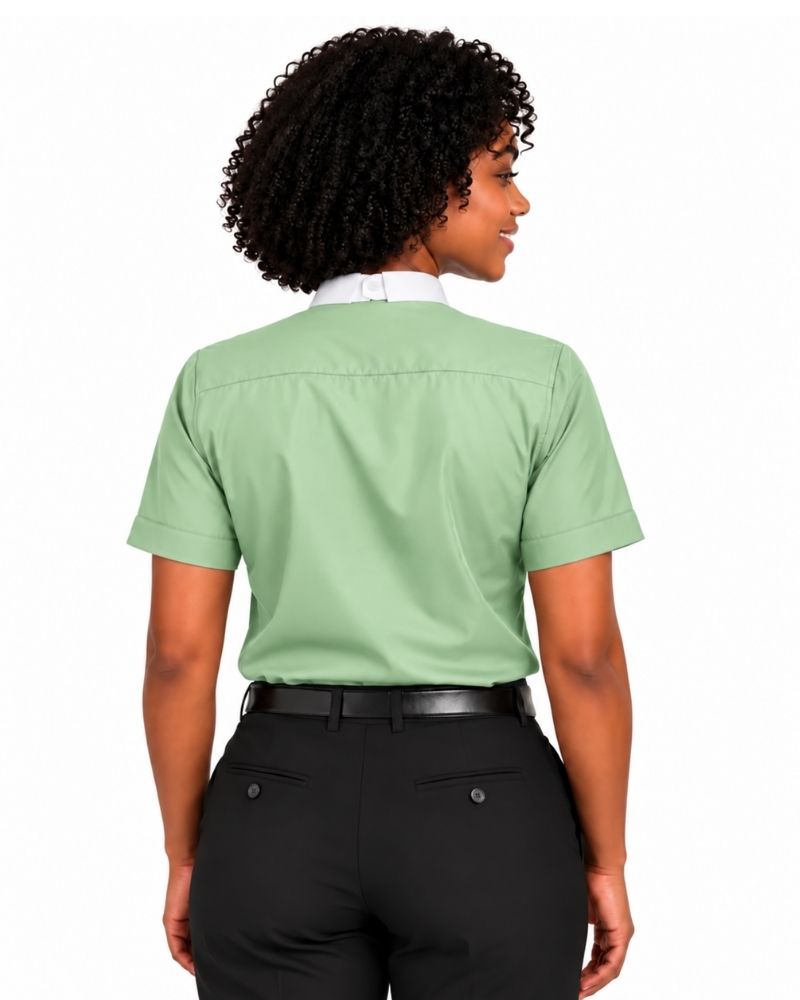 A woman shown from the back wearing a sage green short-sleeve clerical shirt tucked into black pants, against a plain white background.