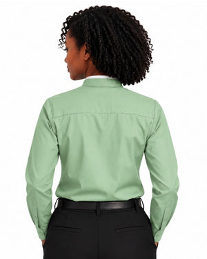 A woman shown from the back wearing a light sage green long-sleeve clerical shirt tucked into black trousers, against a plain white background.