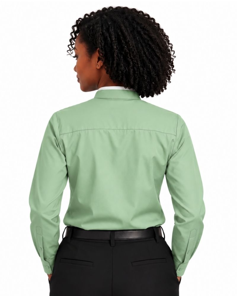A woman shown from the back wearing a light sage green long-sleeve clerical shirt tucked into black trousers, against a plain white background.