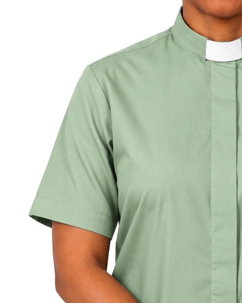 A close-up of a woman wearing a sage green short-sleeve clerical shirt with a white collar.