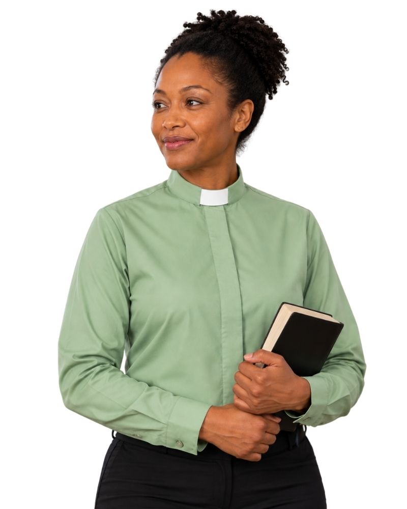A woman wearing a sage green long-sleeve clerical shirt with a white collar, holding a black bibble against a plain white background.