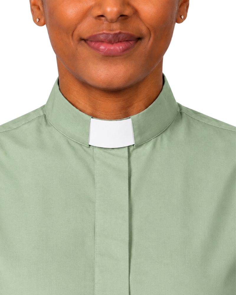 A close-up of a woman wearing a sage green clerical shirt with a white collar tab, shown against a plain white background.