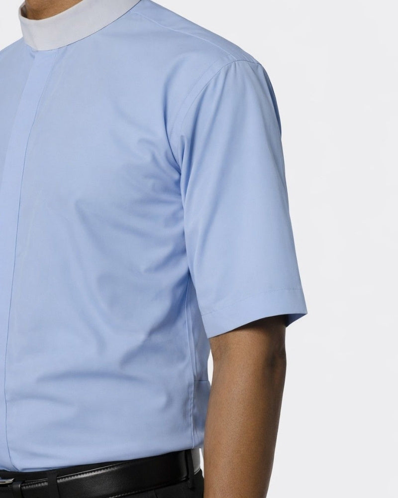Man wearing a light blue shirt with a white collar and black pants on a white background