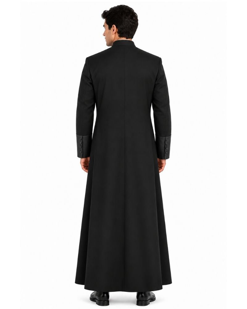 A man viewed from the Black Roman Cassock with Satin Cuffs with a high collar and textured sleeve cuffs, standing against a plain white studio background.