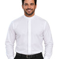 A smiling man wearing a white long-sleeve clerical shirt with a high mock neck collar, paired with black trousers and a black belt, against a plain white background.