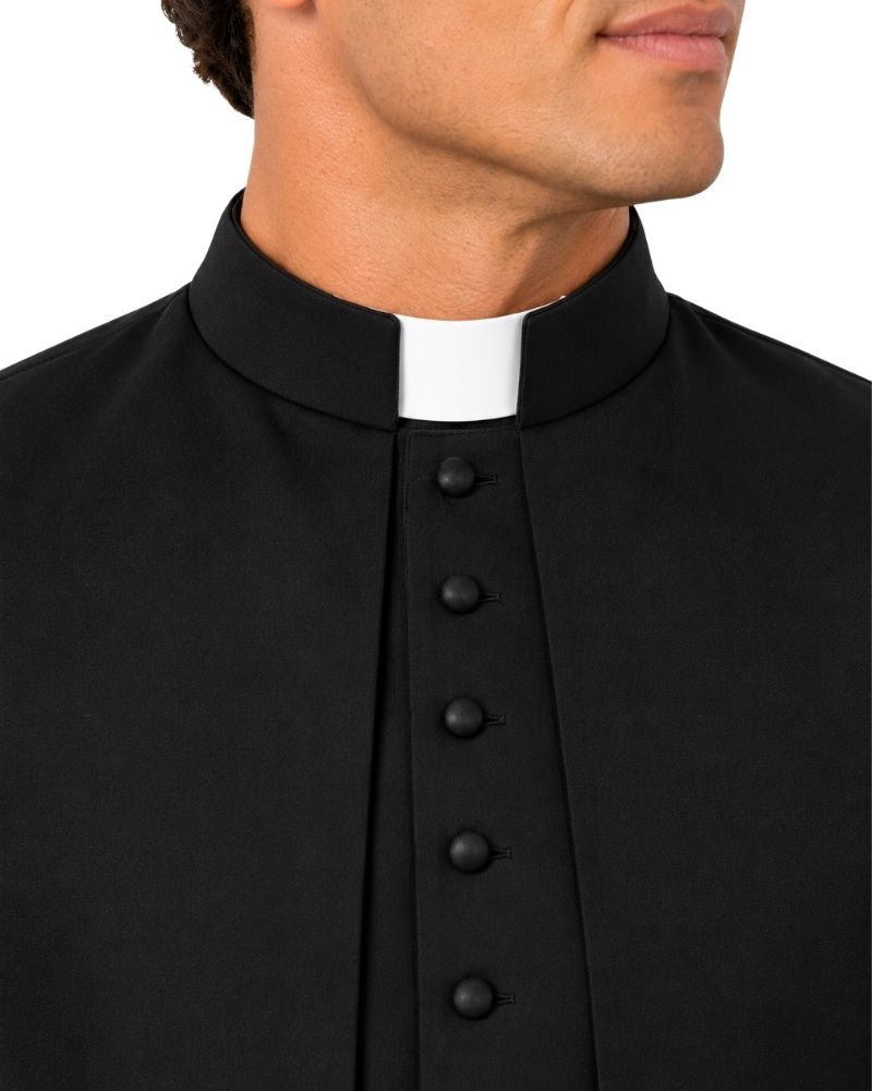 A close-up of a man wearing a black clerical cassock with a white collar and black buttons, shown from the chest up against a plain white background.