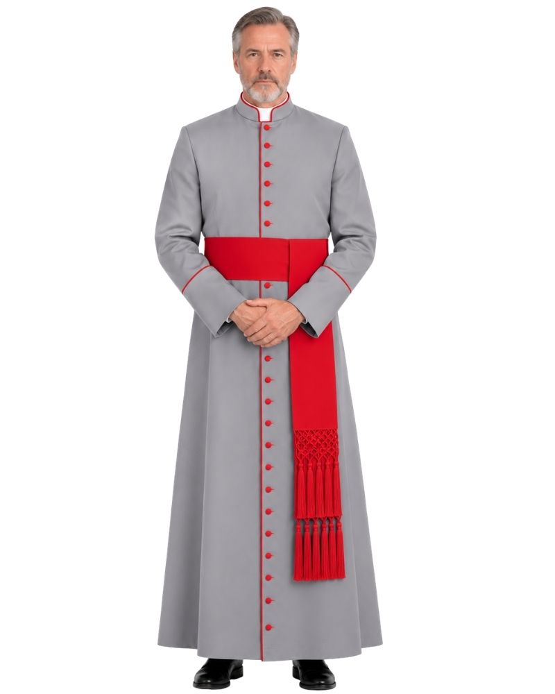 A man modeling a Gray Cassock With Red Trim, a wide red waist sash, and a matching red pectoral cross, photographed against a plain white background.